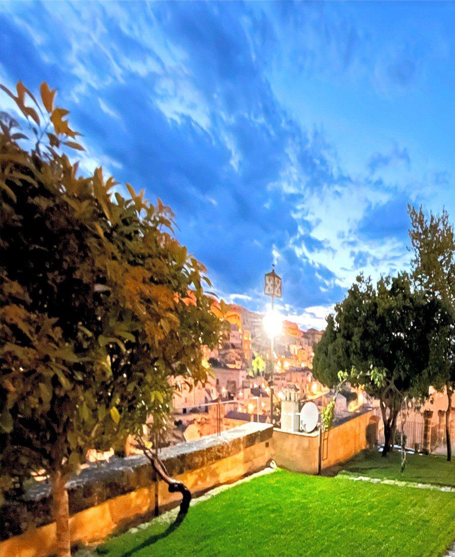 Il prato del giardino e la vista aperta sui Sassi di Matera al tramonto